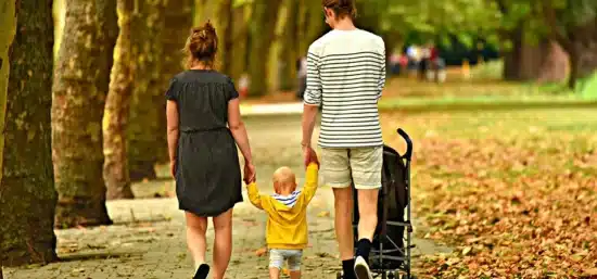 A couple holding their babies hands walking