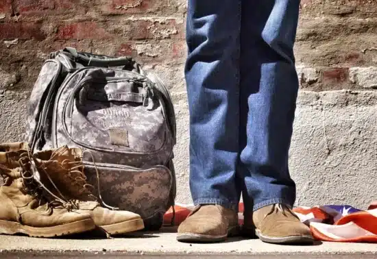 Person standing next to backpack and boots