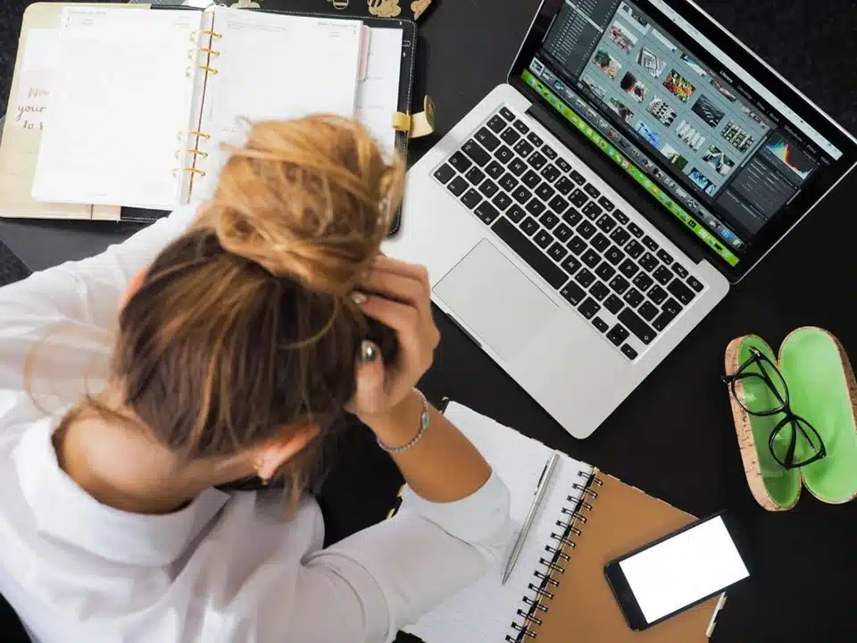 Woman holding her head over a laptop