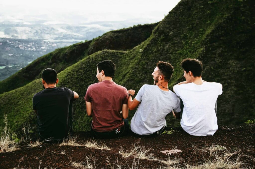 four men sitting on top of a mountain after recovery