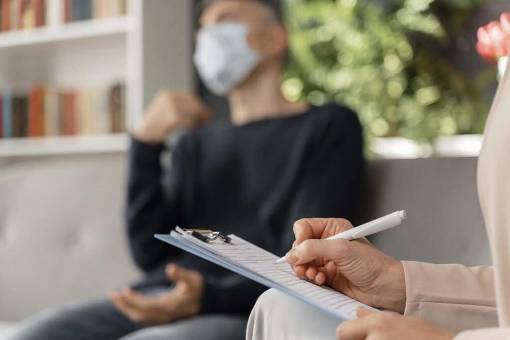 woman therapist taking notes man therapy office with mask 20