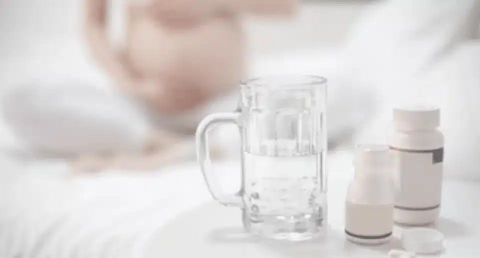 pills and glass sitting in front of a pregnant lady