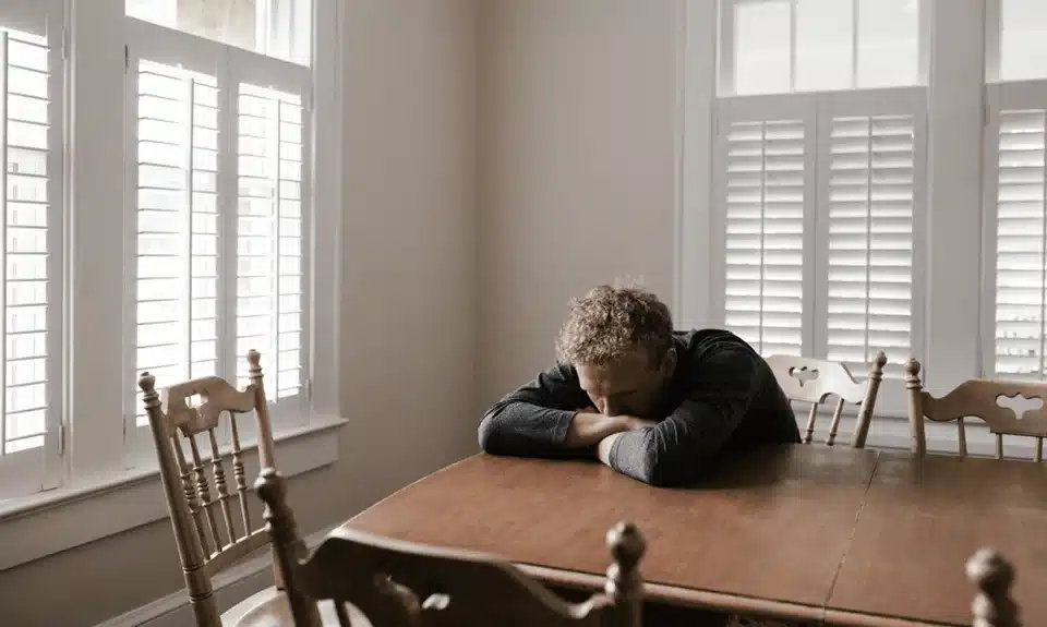 Person with their hand on desk and head on table