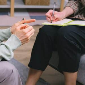 A photo of two people in an addiction treatment session at Opus Health. One person is writing down information while the other is talking.