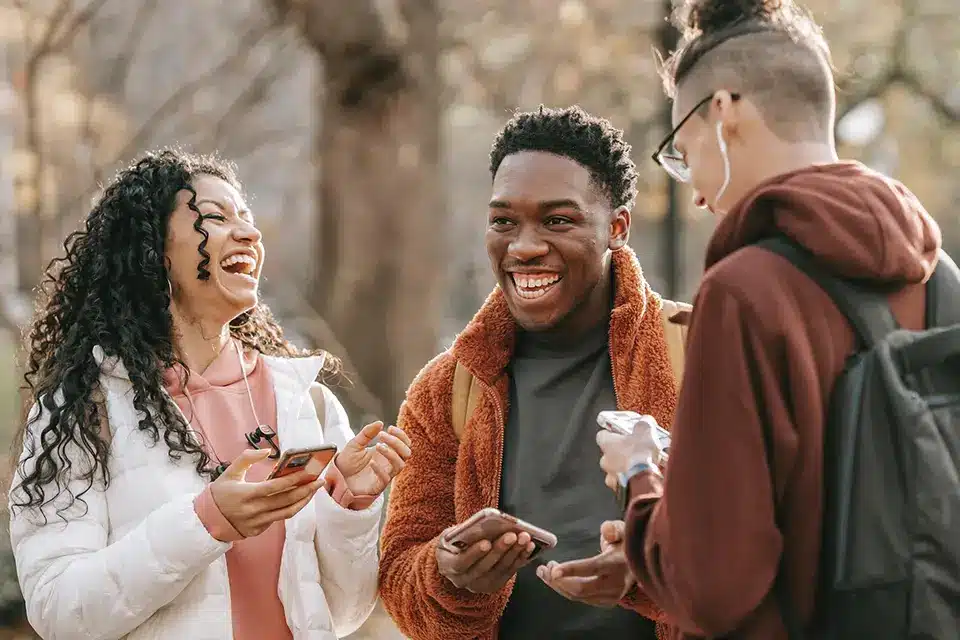 A photo of three people celebrating Mental Health Awareness Month. The people are holding signs that say "Talk to Someone," "Take Care of Yourself," "Seek Help," and "Be Kind."