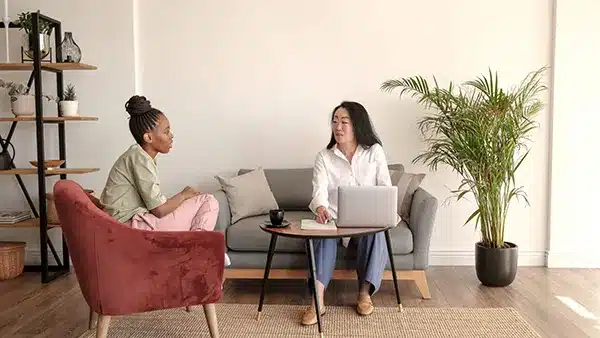 Two women talking to one another at a desk