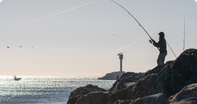 A man fishing from the Wedge jetty in Newport Beach