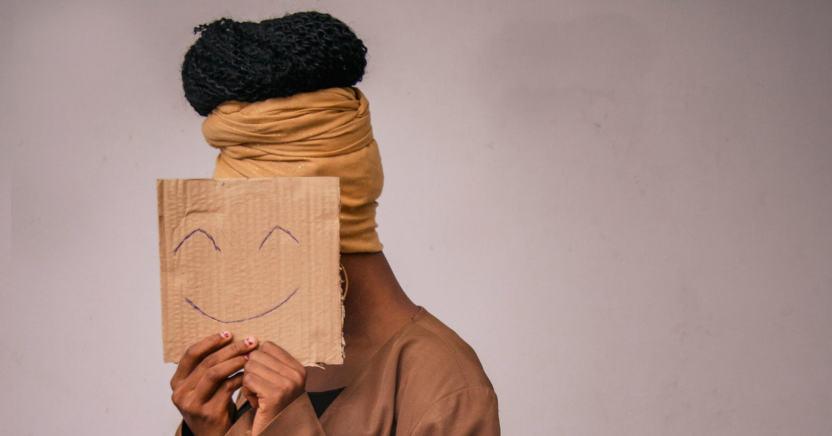 Substance-induced mood disorder concept: Person holding happy face drawing, hiding face. Mental health and addiction issues.