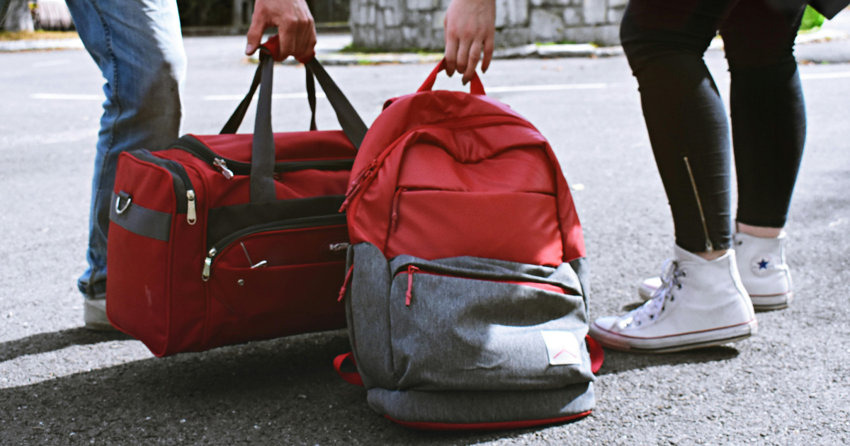 Rehab packing list essentials: People carrying a red duffel bag and backpack, preparing for rehabilitation or travel.