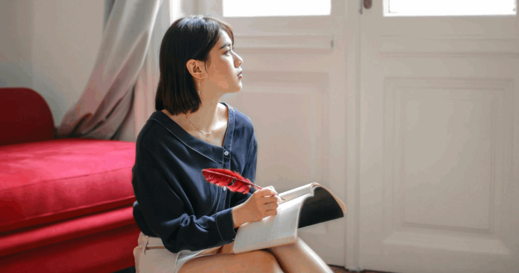 Venlafaxine withdrawal reflection: Young woman thoughtfully writing with a red quill, possibly journaling about anxiety.