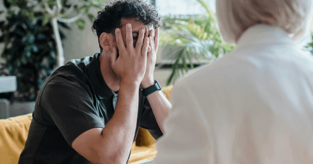 Man covering face during Suboxone withdrawal therapy session. Support for opioid addiction and managing withdrawal symptoms.