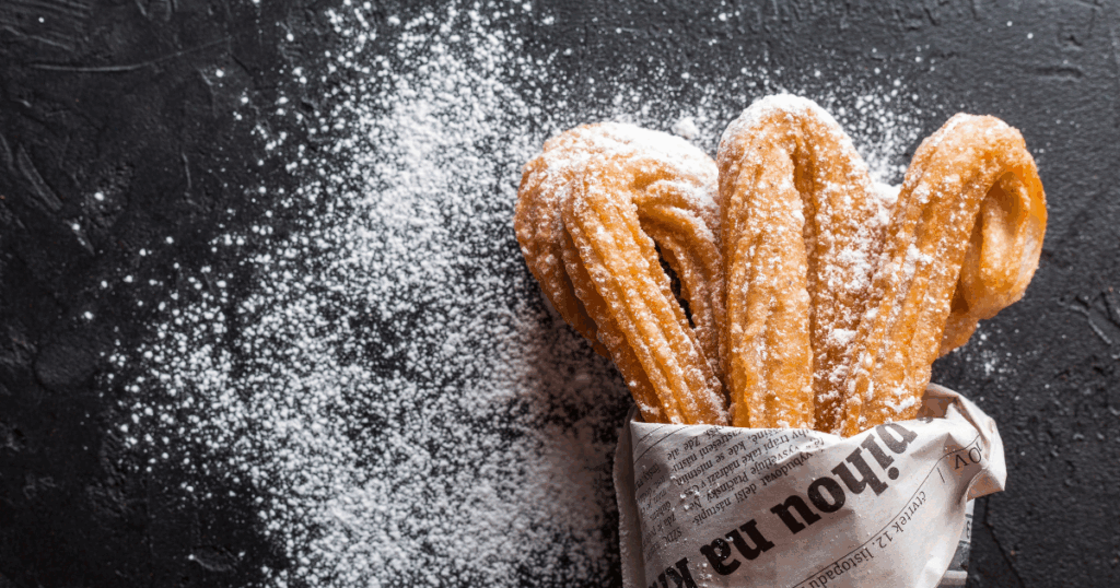 Churros with powdered sugar, a sweet treat often craved during sugar withdrawal, shown in a newspaper cone.