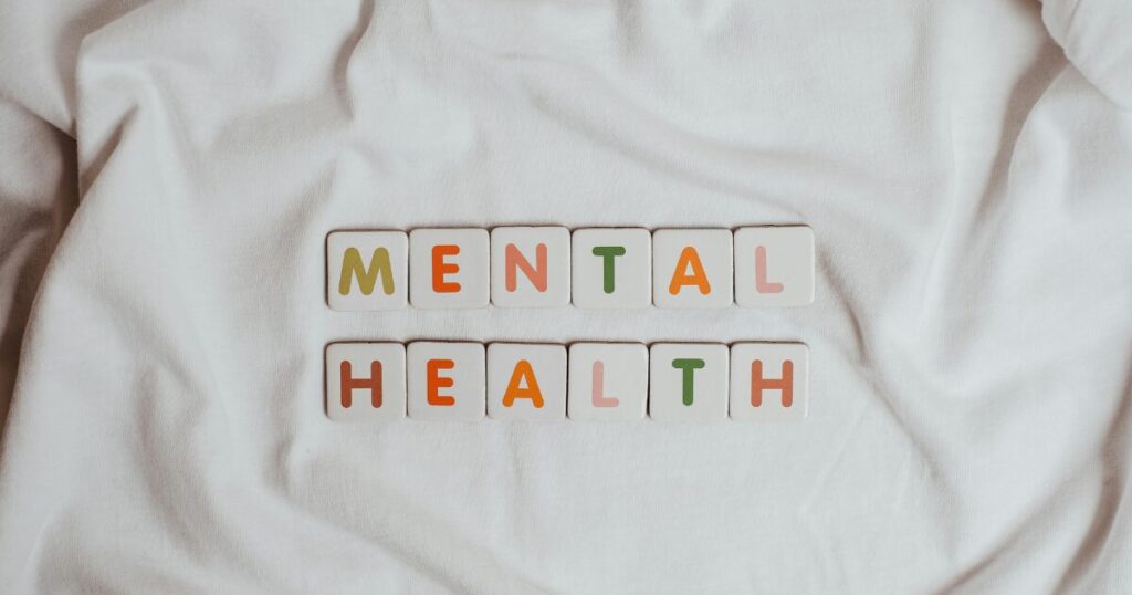 Tiles spelling 'MENTAL HEALTH' on a white fabric background, conveying mental health awareness.
