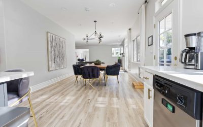 Modern dining room with black velvet chairs, gold accents, wood floors, and stylish lighting in a Santa Ana home.