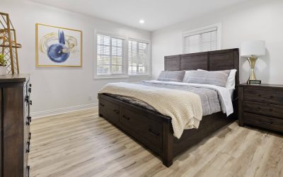 Modern bedroom with a dark wood bed frame, nightstand, and light wood floors in a Santa Ana home. Interior design.