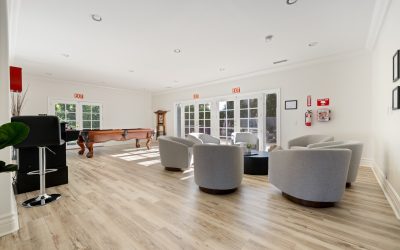 Spacious game room with pool table, lounge area with gray chairs, and wood flooring in Santa Ana, CA. Interior design.