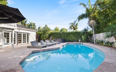 Luxury backyard pool with lounge chairs, palm trees, and blue sky. Santa Ana home with outdoor living and relaxation.