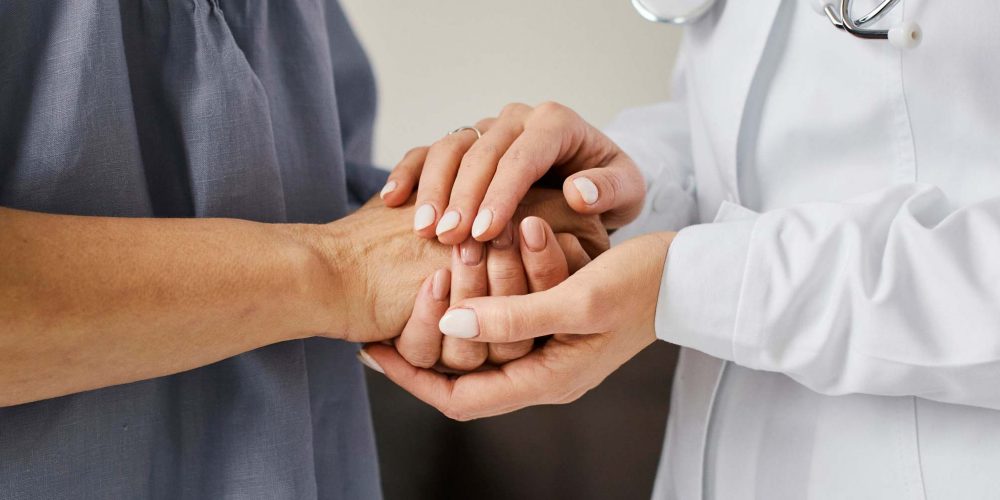 a doctor supportively holding hand with a patient