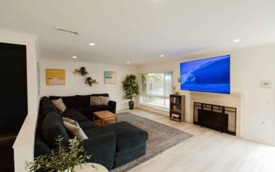 LP Facilities Tour: Modern living room with sectional sofa, TV with surfing scene, and stylish decor. Luxury property.