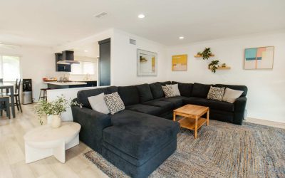 LP Facilities Tour: Modern living room with large sectional sofa, open kitchen, and stylish decor. CariHouse interior.