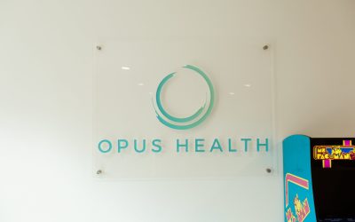 Opus Health facilities sign. Modern office interior with company logo and branding, showcasing a health and wellness center.