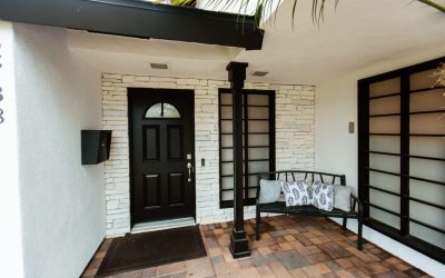 LP Facilities Tour: Entrance with black door, stone accent wall, bench, and brick patio, showcasing our welcoming assisted living home.