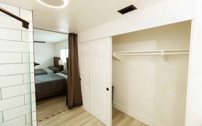 Cari House facilities tour: View of a bedroom with two beds, a closet with sliding doors, and a tiled bathroom with shower.