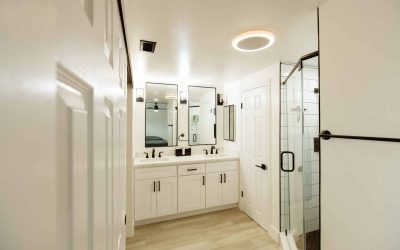 CariHouse bathroom facilities tour: Modern white bathroom with double vanity, shower, and sleek design elements.