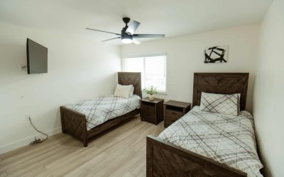 LP Facility Bedroom: Two beds, nightstands, ceiling fan, and TV. Tour our comfortable and modern living spaces today!