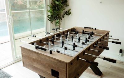 LP Facility Tour: Foosball table in a game room with a pool visible through a sliding glass door. Fun amenities for staff.
