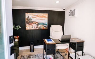 Modern home office setup with black accent wall, abstract art, desk, and ergonomic chair. Stylish workspace design.