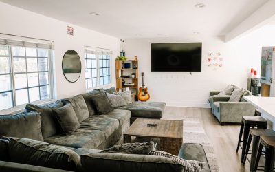 Cozy living room interior with large gray sectional sofa, guitar, and TV. Home living space design.