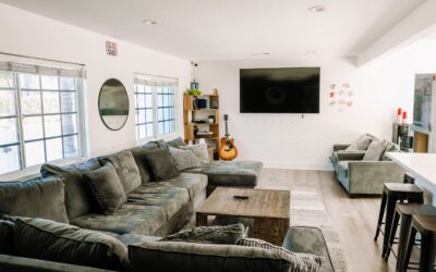 Cozy living room interior with large gray sectional sofa, guitar, and TV. Home living space design.