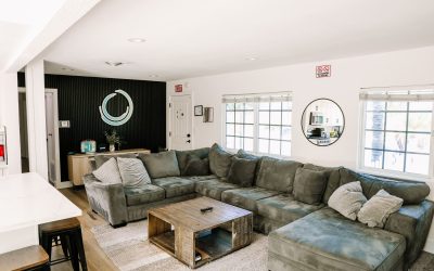 Modern living room interior with a large grey sectional sofa, wooden coffee table, and stylish decor. Bright, inviting space.