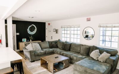 Modern living room interior with a large grey sectional sofa, wooden coffee table, and stylish decor. Bright, inviting space.