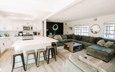 Open-concept living: Modern kitchen with island, stools, and spacious living room with sectional sofa. Bright, inviting home interior.